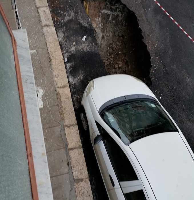 Manto stradale cede per la pioggia, ruota di un'auto nella buca